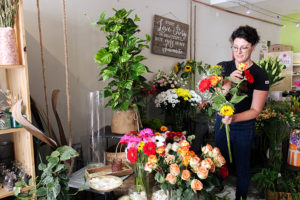 Une fleuriste dans sa boutique qui compose un bouquet de fleurs fraiches.